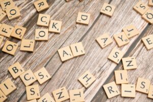 Wooden letter tiles scattered on a textured surface, spelling 'AI'.